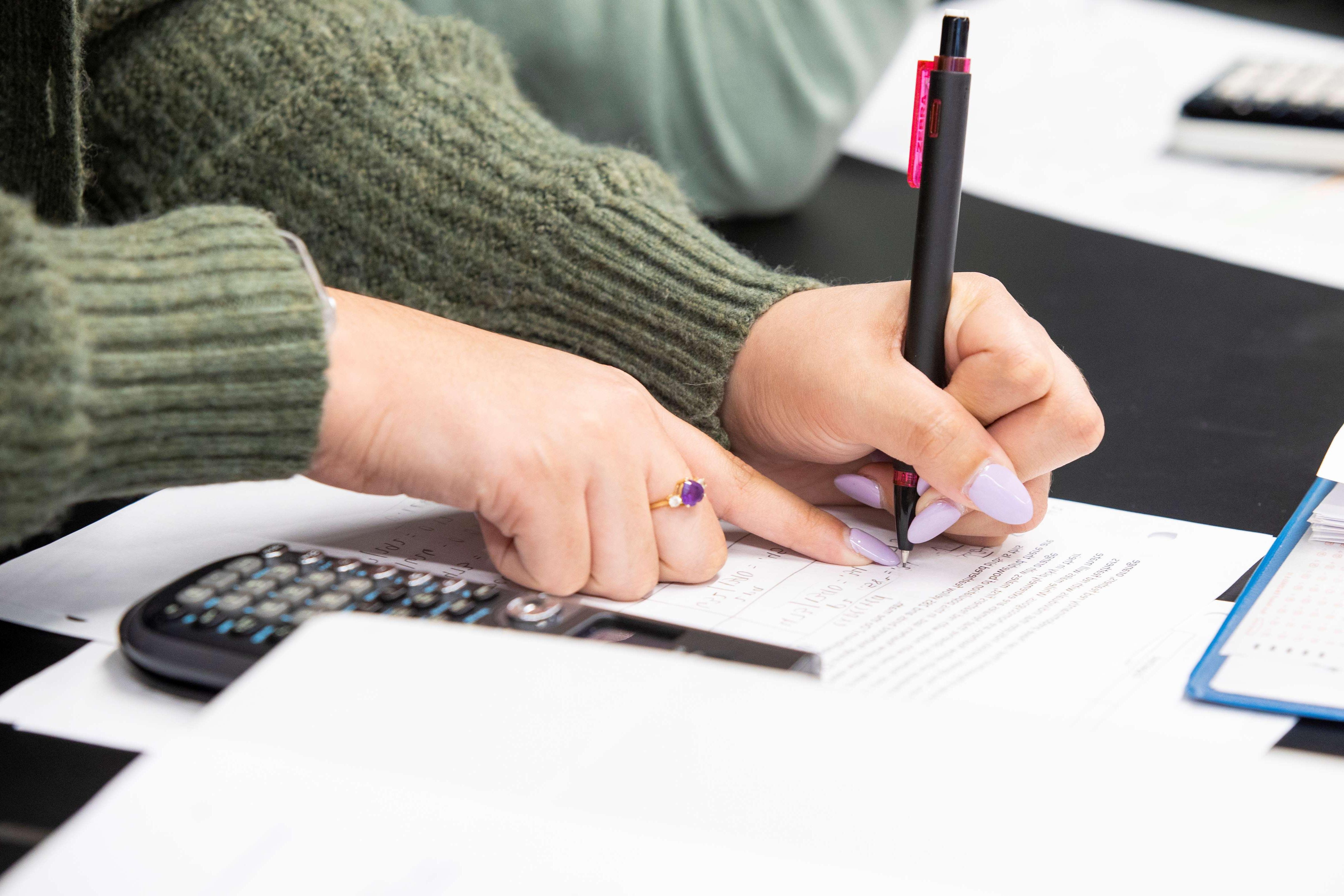 Girl completing calculations with a calculator.