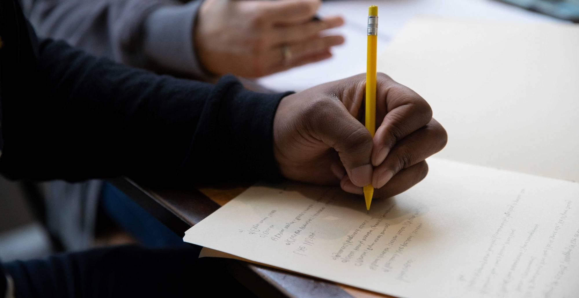 A hand writing with a pencil