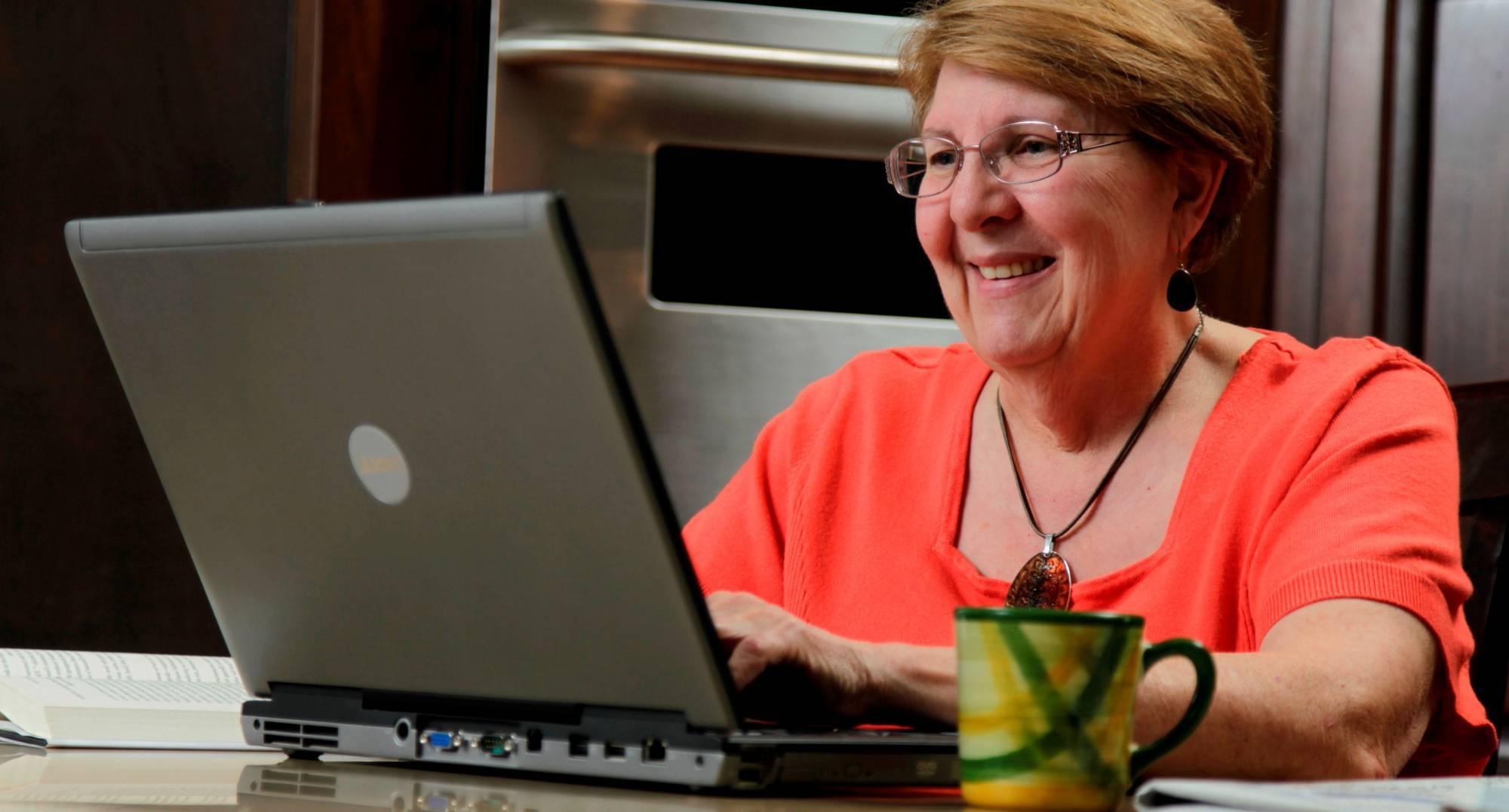 Lady looking at her computer in her kitchen