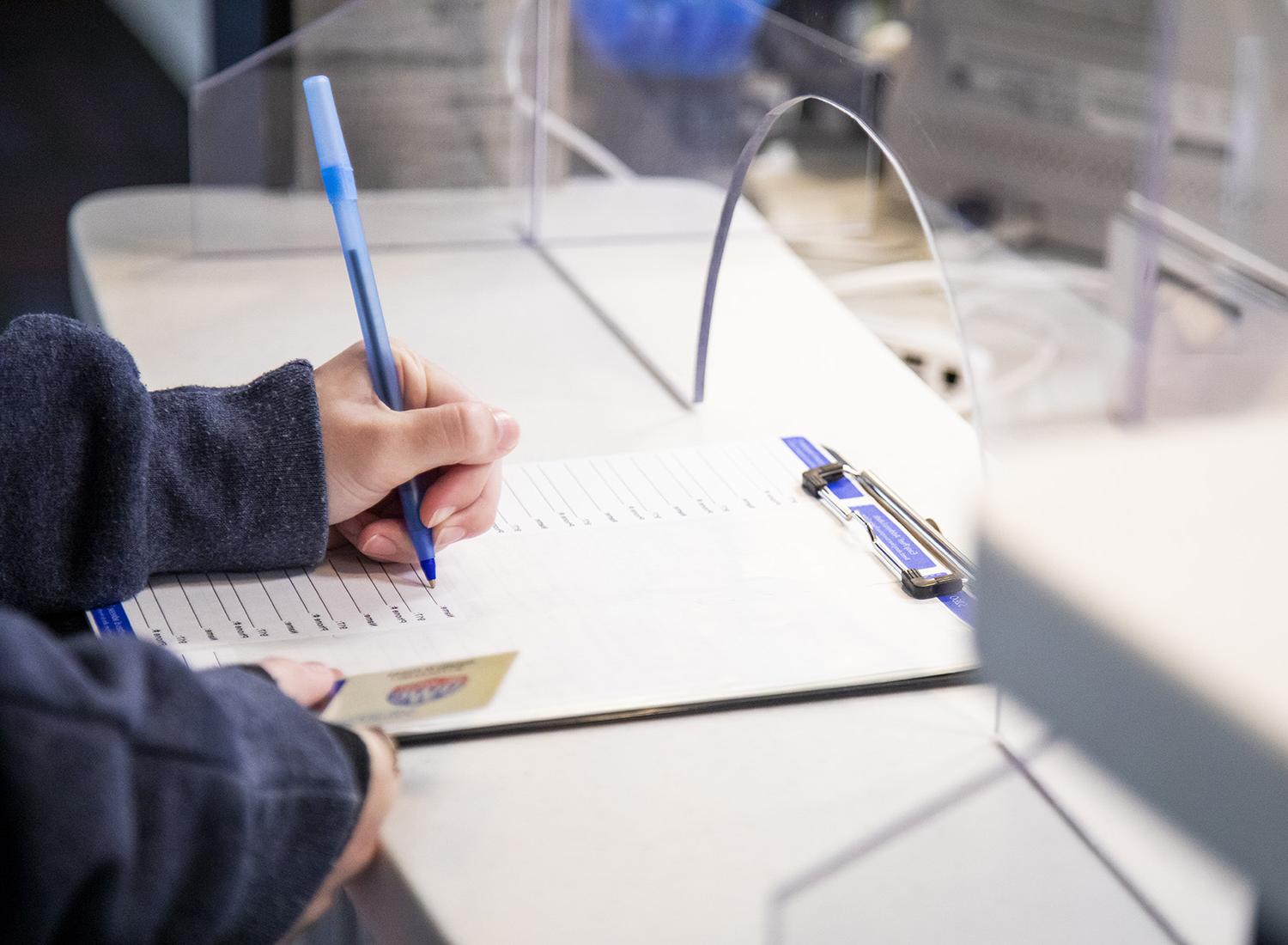 Student filling out paperwork at the Health Services desk